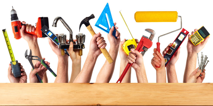 Foto Hände, die Werkzeuge über einem Holzbrett hochhalten.